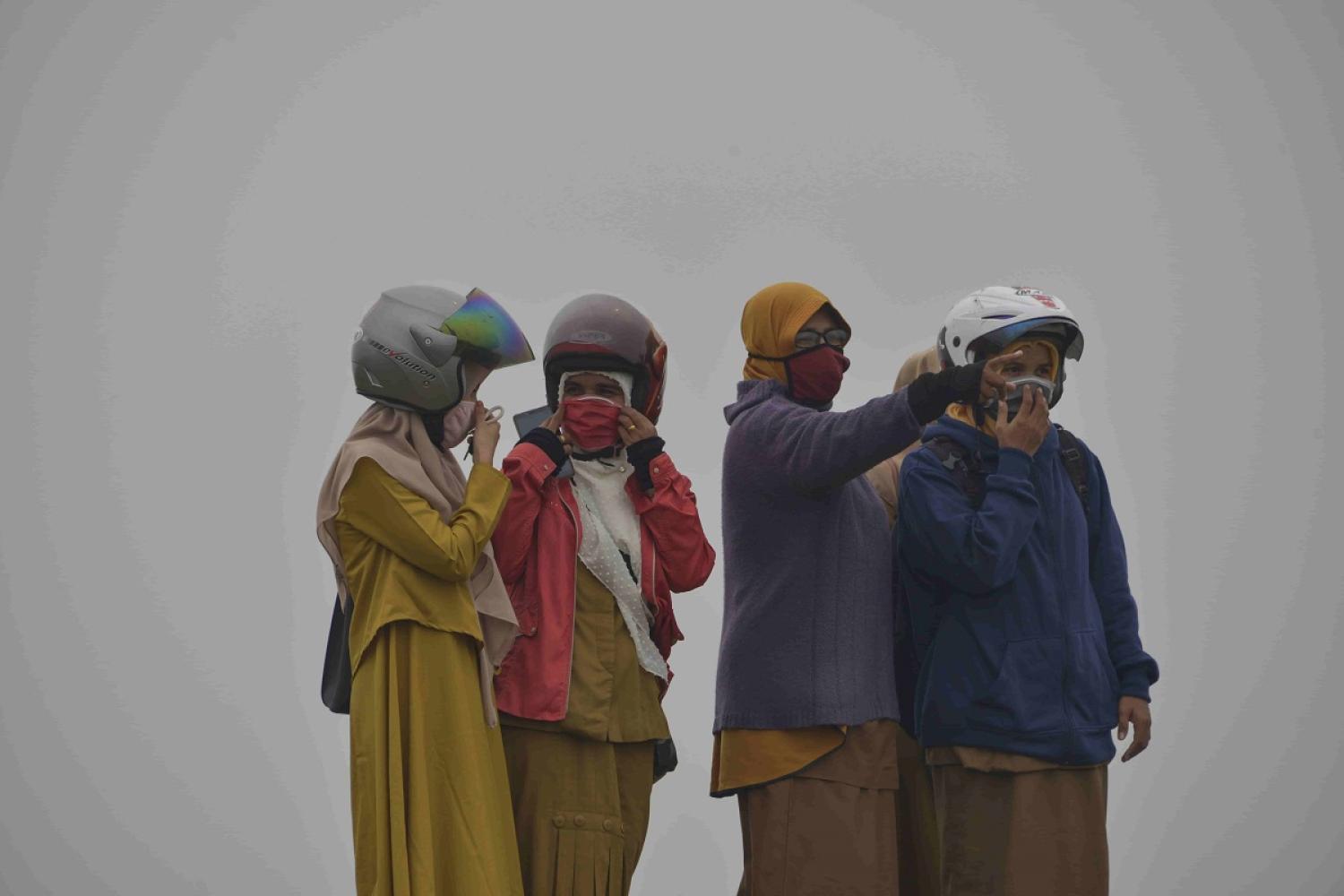 People wear masks due to thick haze caused by smog-belching forest fires in Indonesia (Chaideer Mahyuddin/AFP via Getty Images)